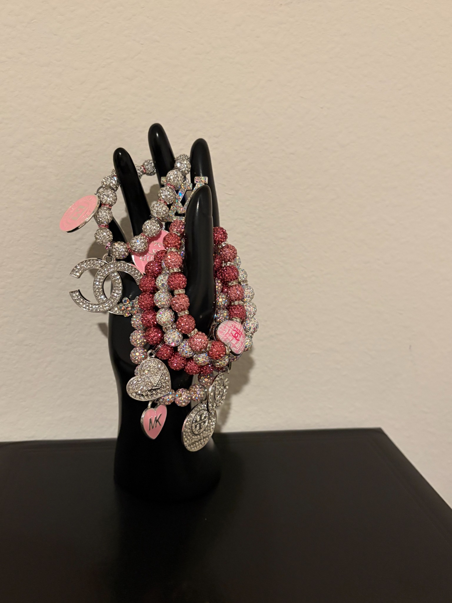 Pink and silver chunky bling bracelets with sparkling beads and dangling charms on a display stand
