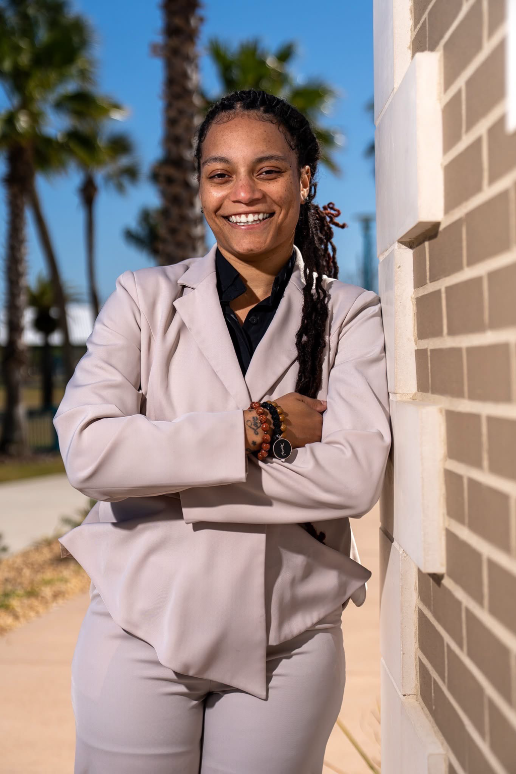 Jasmine Harris smiling outdoors in a light-colored suit