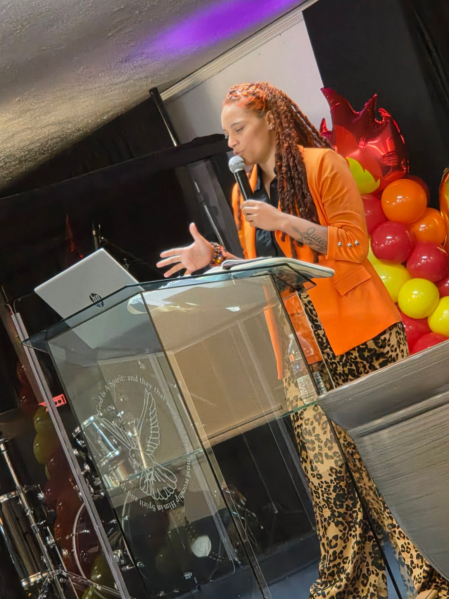 Jasmine Harris teaching at a lectern with an open Bible and microphone