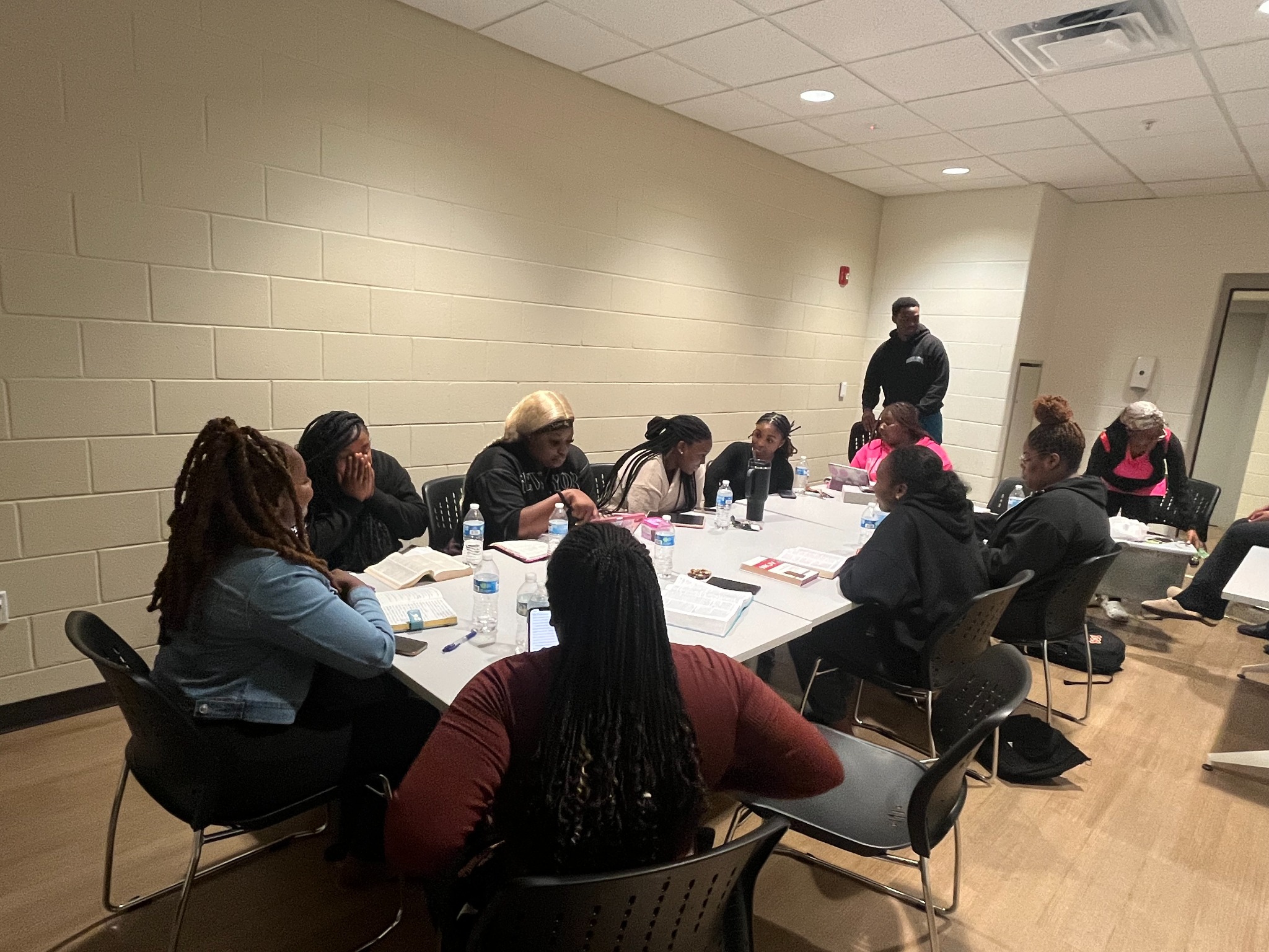 A mentorship group gathered around a table with open Bibles for study and discussion